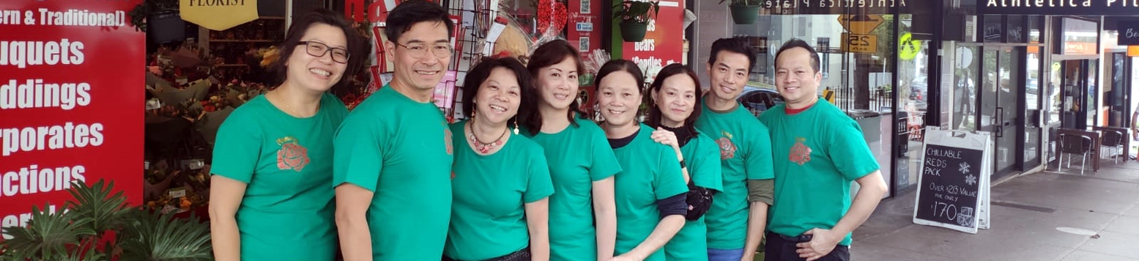 A group of people wearing green shirts standing in front of a store.