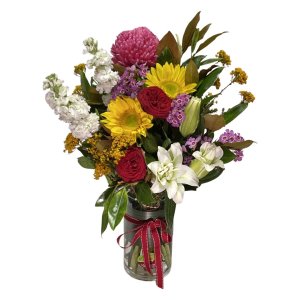 A vibrant flower arrangement in a glass vase, showcasing a variety of colorful flowers and lush greenery