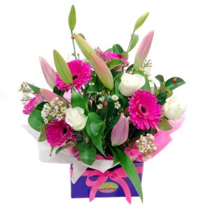 A purple box filled with pink and white flowers arranged in a beautiful floral display