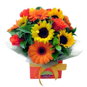 A beautiful flower arrangement in a box, featuring a mix of colorful blooms and greenery