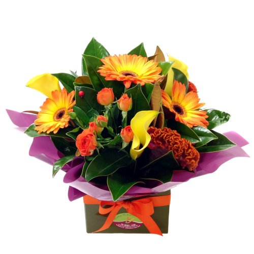 A flower arrangement featuring orange and yellow flowers in a box